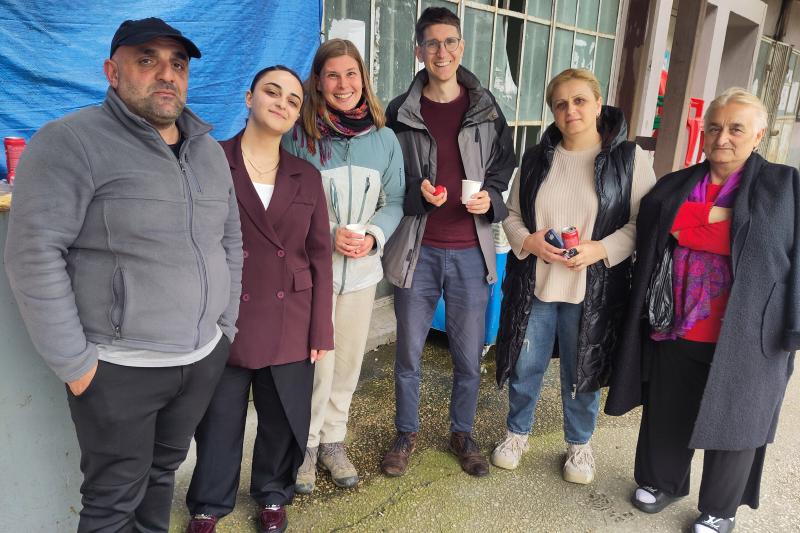 Einige Personen im Kreis stehen mit Wein und rotem Ei in der Hand.